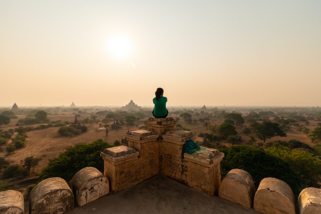 lone person sits on top of a temple overlooking old bagan myanmar